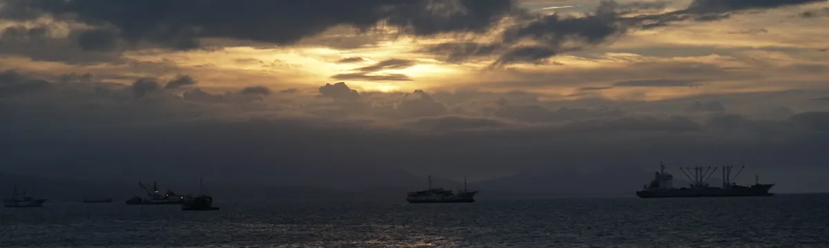 איי שלמה: Serene sunset with ships silhouetted against the cloudy sky over Solomon Islands.