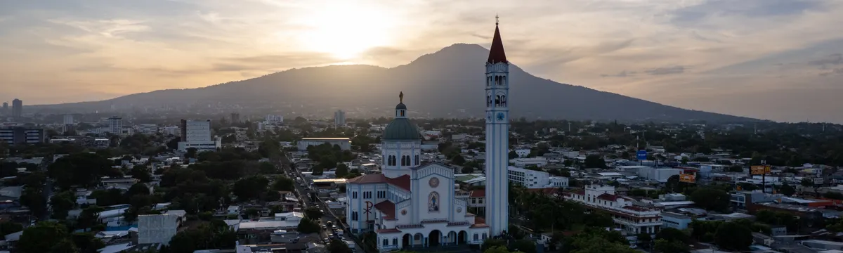 אל סלבדור: Breathtaking aerial view of San Salvador city skyline with a basilica at sunset.