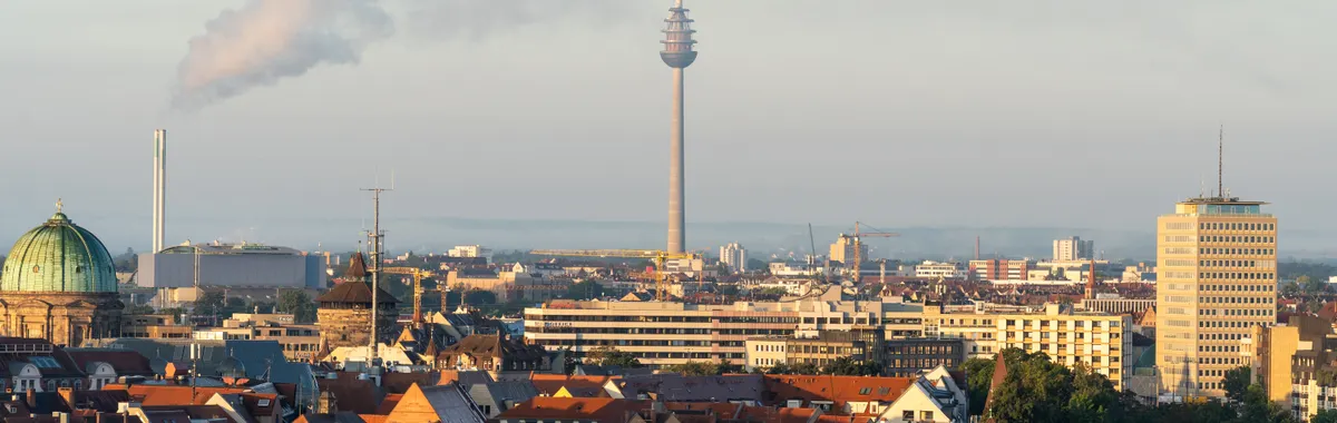 Panoramic view of Stuttgart city skyline featuring the Fernsehturm tower and city rooftops at dawn.