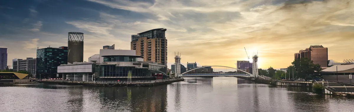 A stunning view of Salford Quays at sunset with modern architecture reflecting on the water.