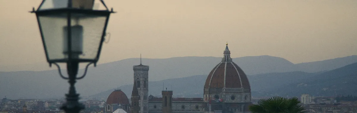 A view of Florence with the iconic Duomo and distant hills under a twilight sky.
