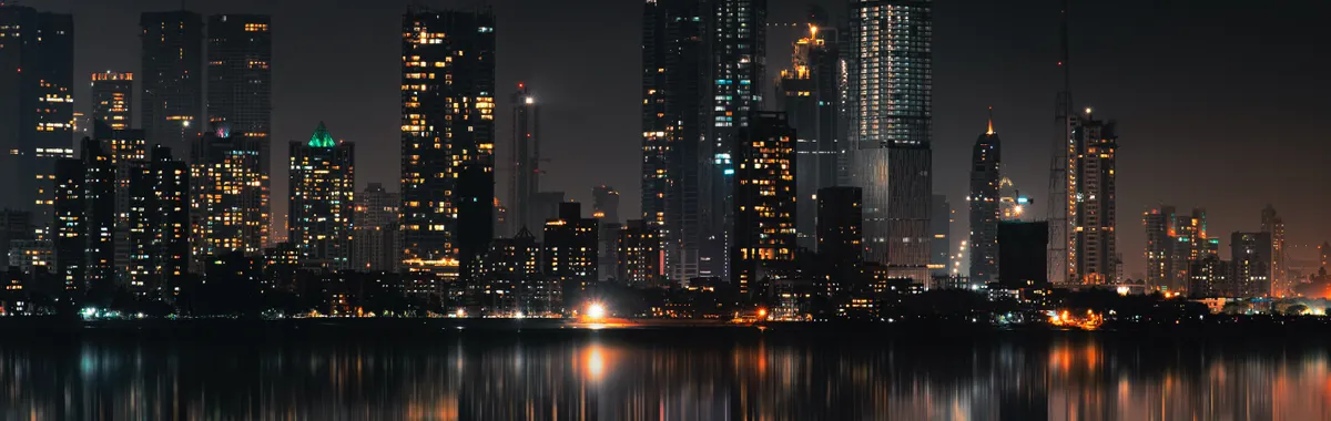 Captivating night view of Mumbai skyline with skyscrapers and reflections on still water.