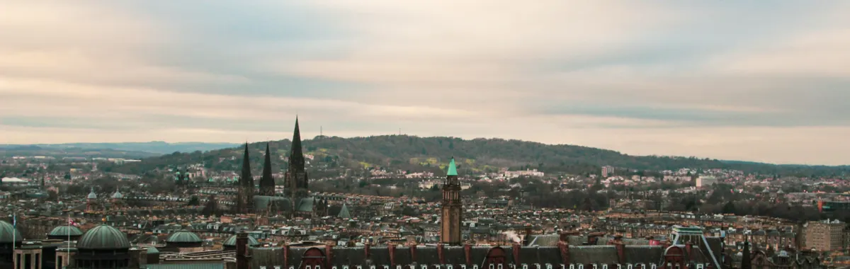 Aerial view of Edinburgh showcasing its historic architecture under a cloudy sky.