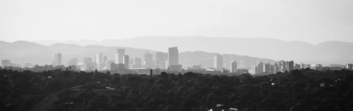 Grayscale view of Pretoria's skyline with prominent tall buildings and hills.