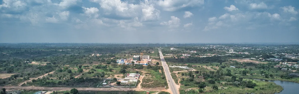 חוף השנהב: Aerial view of Yamoussoukro, Côte d'Ivoire, showcasing suburban landscapes, roads, and a lake.