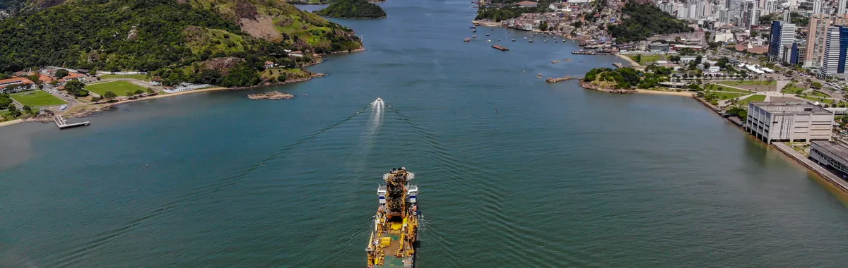 ברזיל: Aerial view of Vitória, Brazil, showcasing the city's waterfront and a large ship navigating the channel.