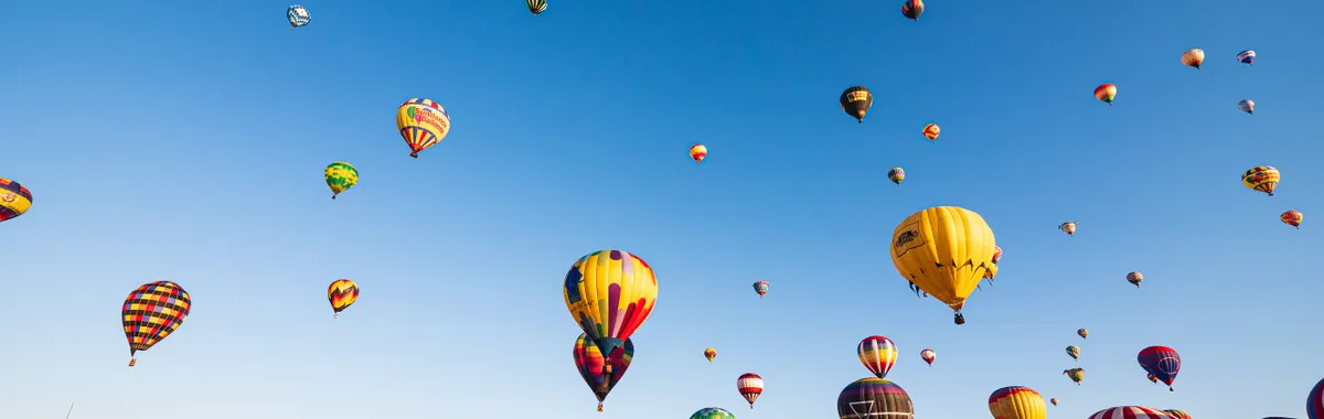 Colorful hot air balloons fill the sky during a lively festival in Albuquerque, New Mexico.