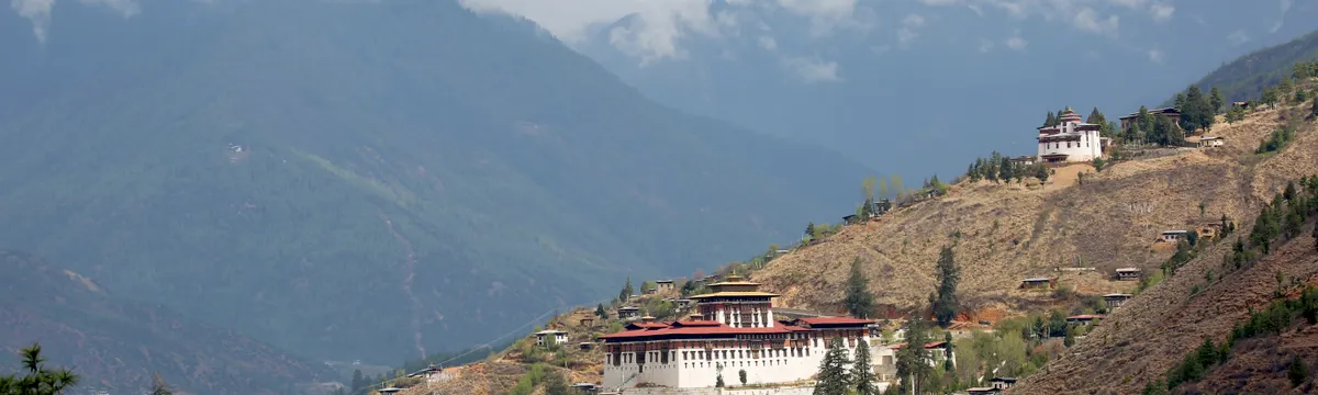 בהוטן: Scenic view of Paro Valley with Rinpung Dzong, surrounded by mountains and clouds in Bhutan.