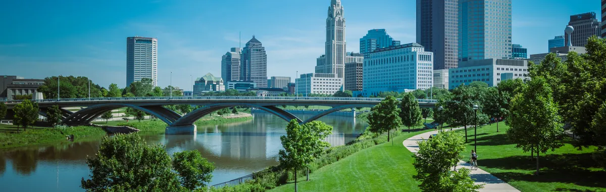 View of Columbus skyline with modern skyscrapers and green park along the river.