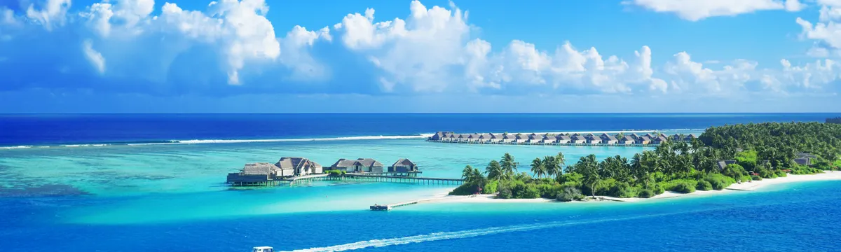 האיים המלדיביים: Crystal clear waters surround a luxurious Maldives resort under a bright blue sky.