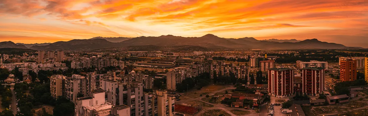Stunning aerial view of Podgorica cityscape at sunset, featuring vibrant orange skies and architecture.