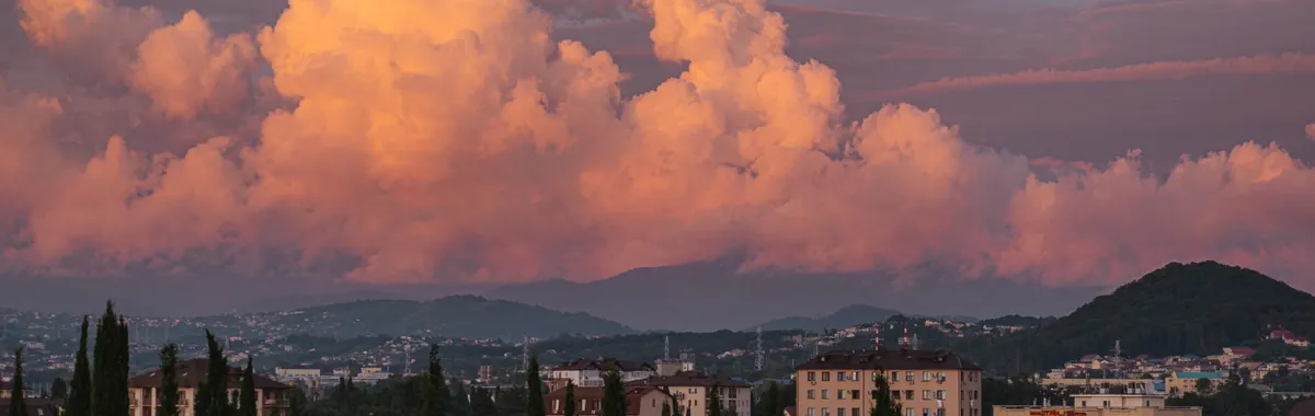 Beautiful Sochi cityscape with dramatic cumulus clouds during sunset.